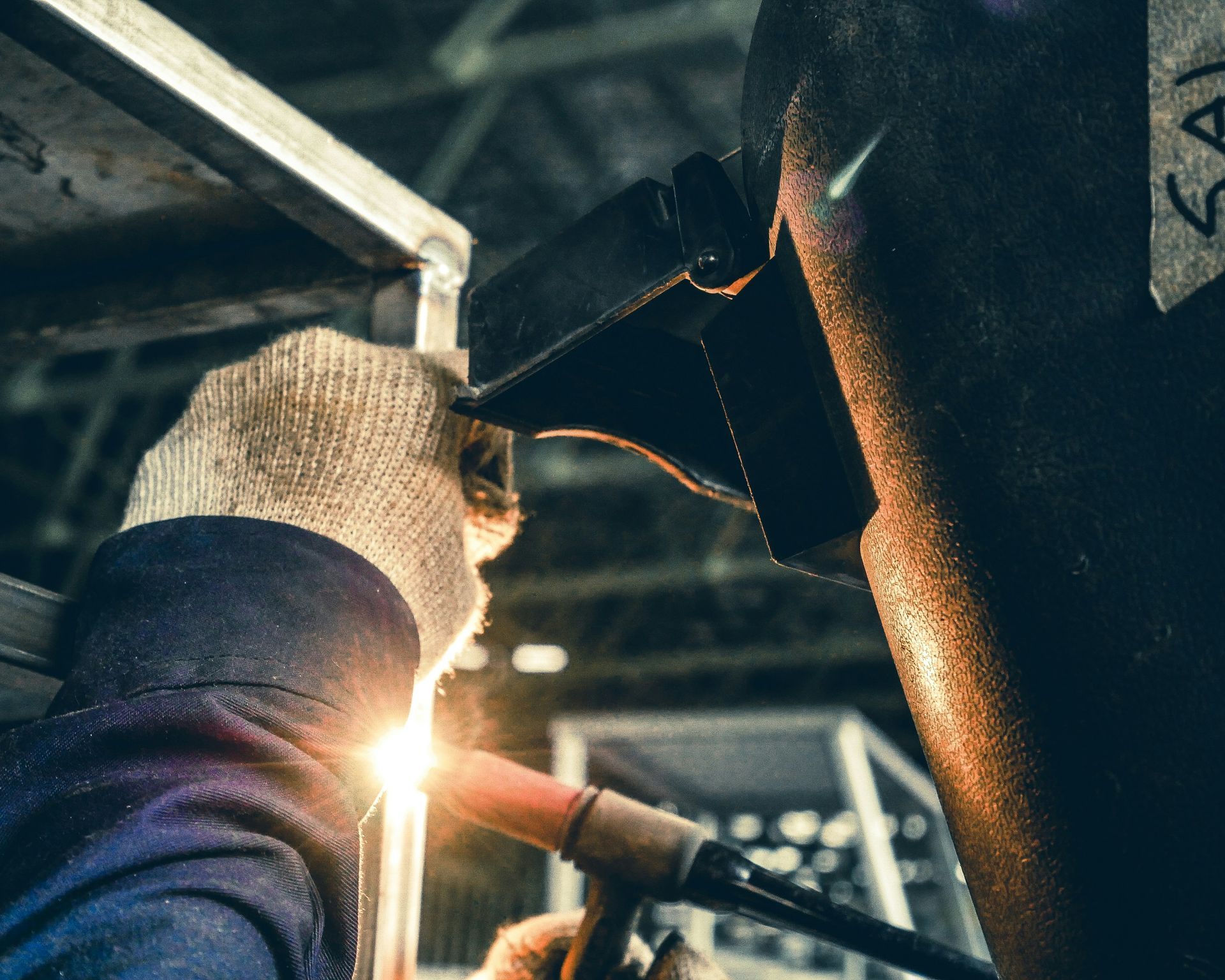 A man is welding a piece of metal in a factory.