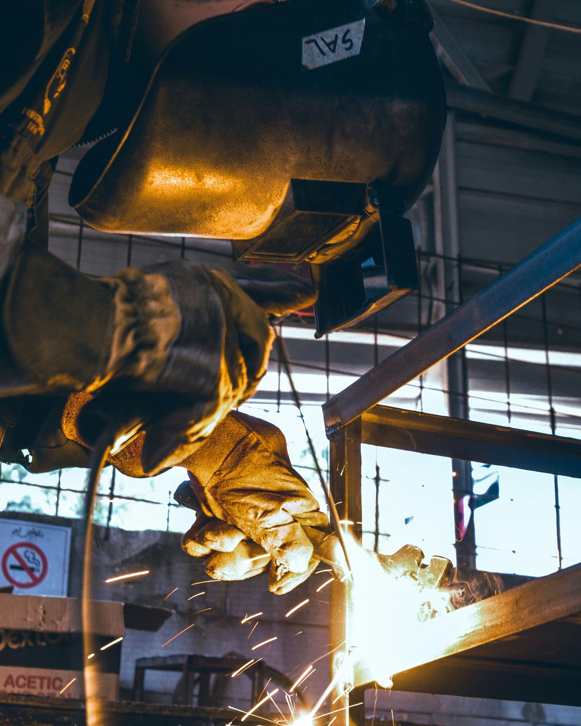 A man is welding a piece of metal in a factory.