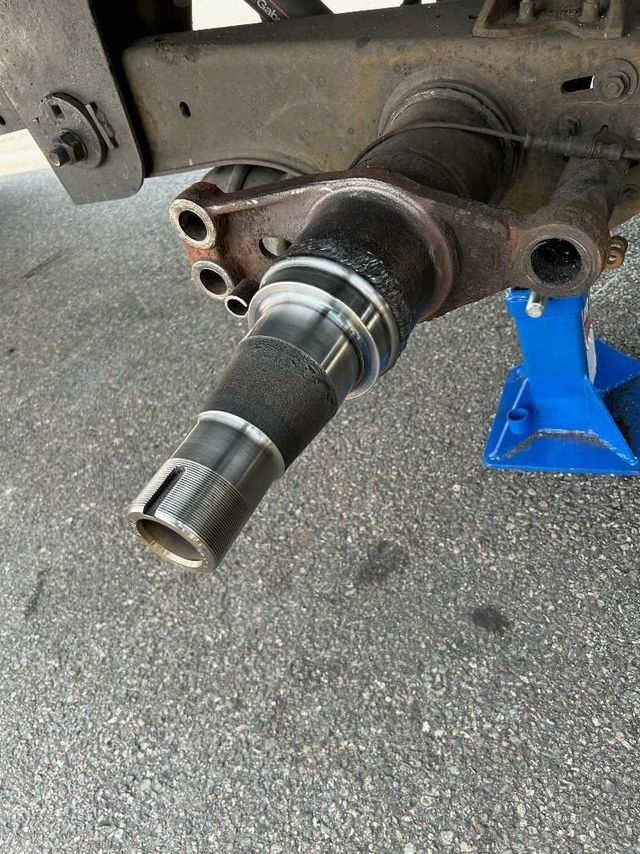 Car wheel hub and axle spindle on jack stand, showing exposed brake components.