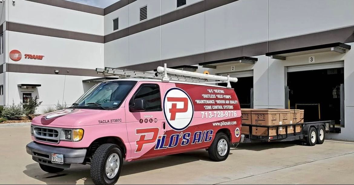 Pink and red service van with trailer in front of a building, Trane logo visible.