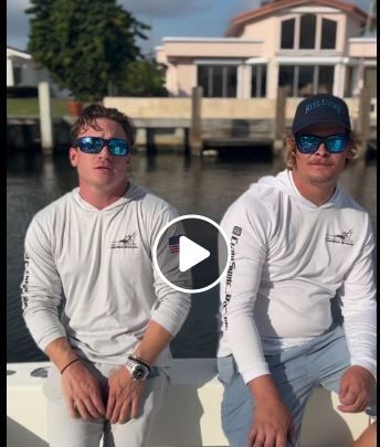 two men wearing sunglasses are sitting on a boat .