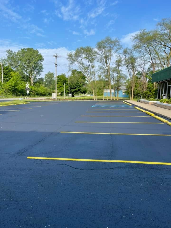 Empty asphalt parking lot with yellow and blue painted lines under a blue sky.