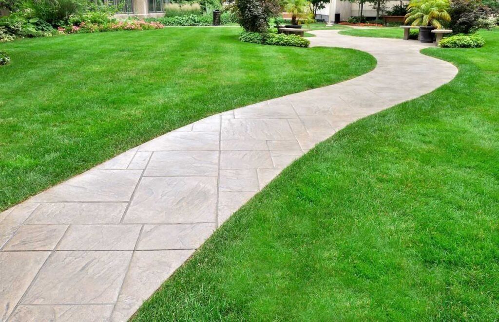 Curved stone walkway through a green lawn in a landscaped yard