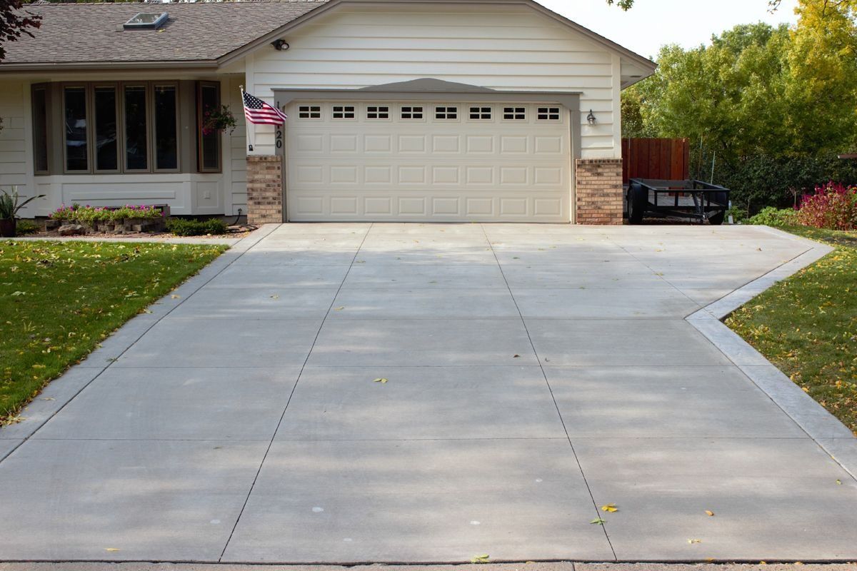 Suburban house with a wide concrete driveway leading to a two-car garage