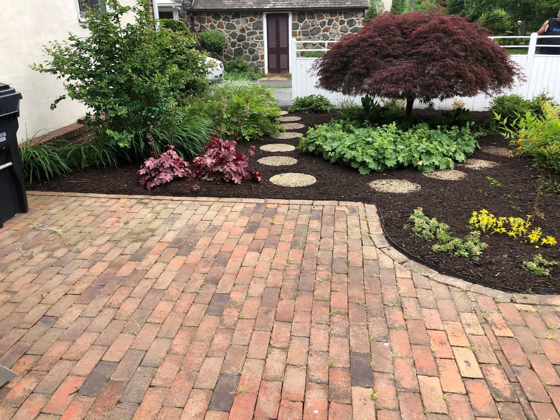 Brick driveway leading to a landscaped front garden with stepping stones and shrubs