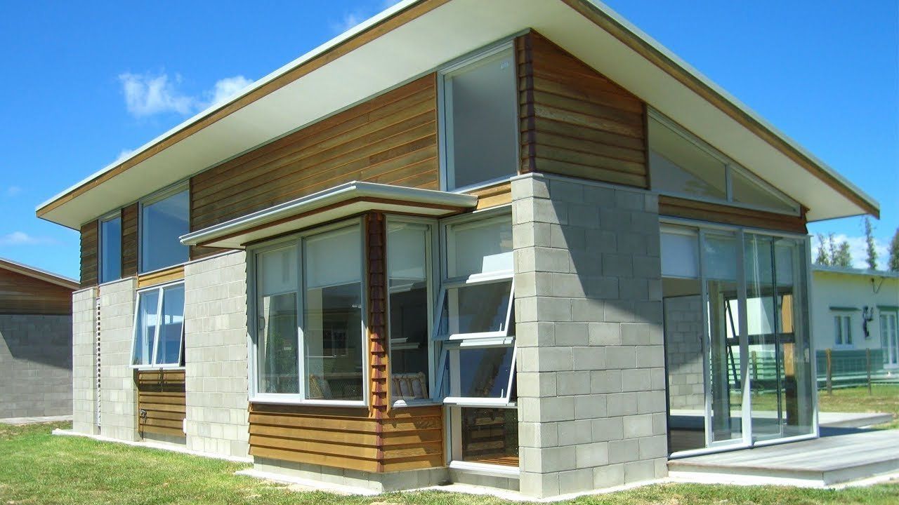 Modern house exterior with wood and gray block siding, large windows, and a sloped roof