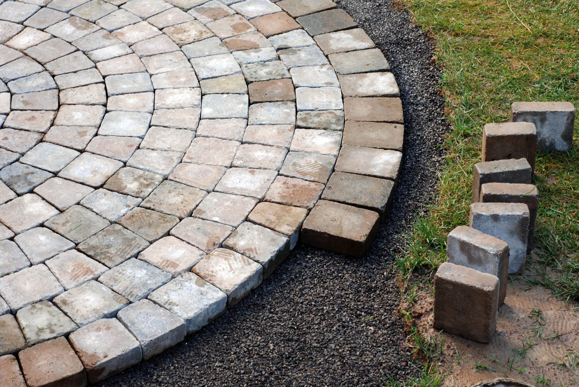Curved stone patio paving with a gap, bordered by gravel and small stacked stones