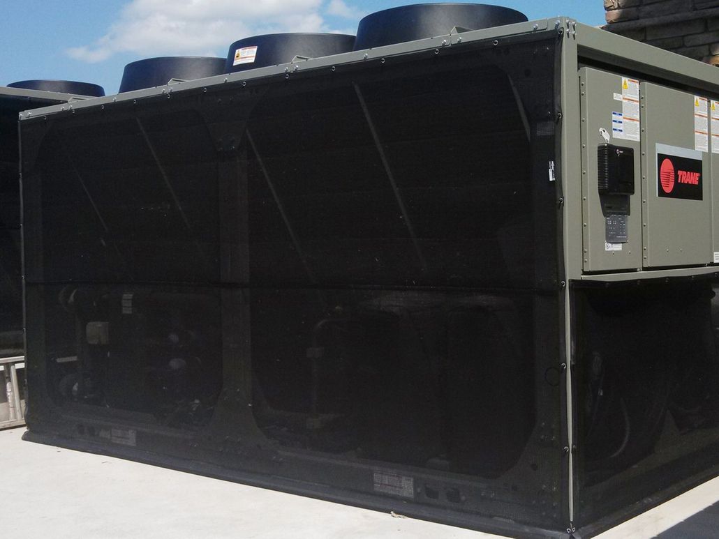 Large, rectangular HVAC unit on a rooftop, with black mesh sides and dark exhaust vents. A control panel is visible.
