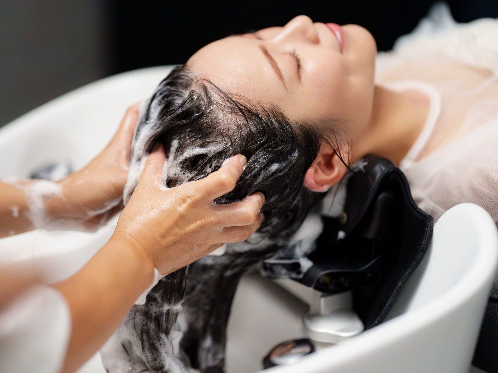 A woman is getting her hair washed in a sink at a salon.
