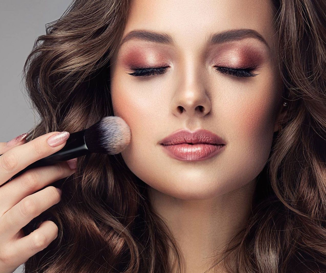 A woman is applying makeup to her face with a brush.