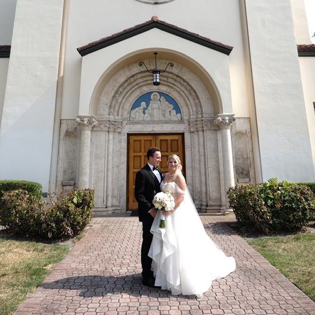 A bride and groom pose in front of a church