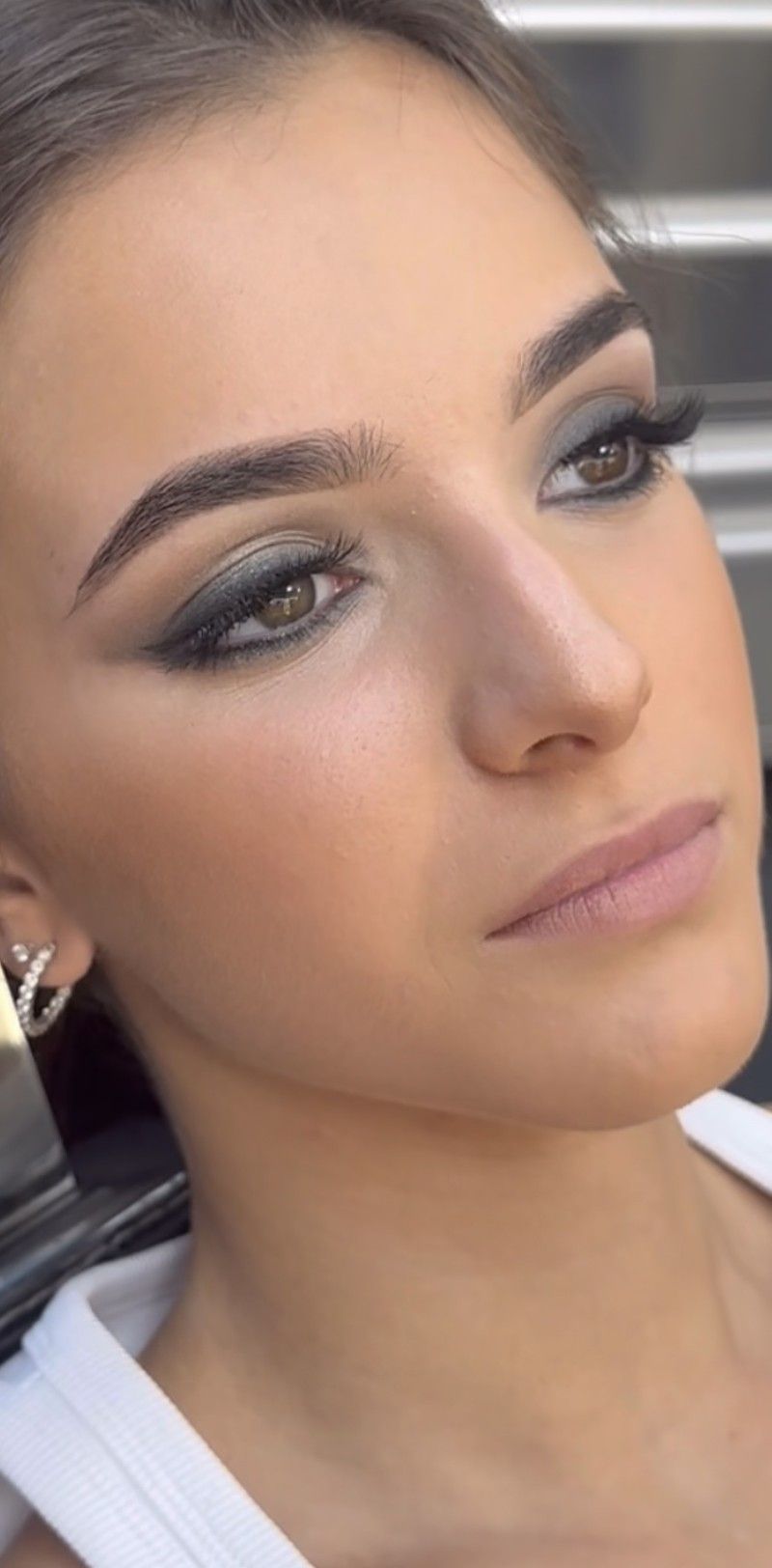 A close up of a woman 's face with makeup and earrings.