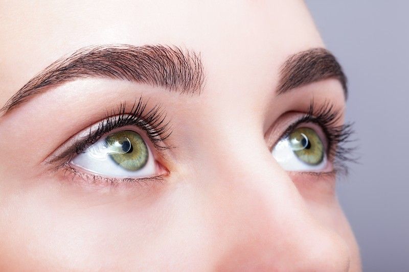 A close up of a woman 's green eyes looking up.