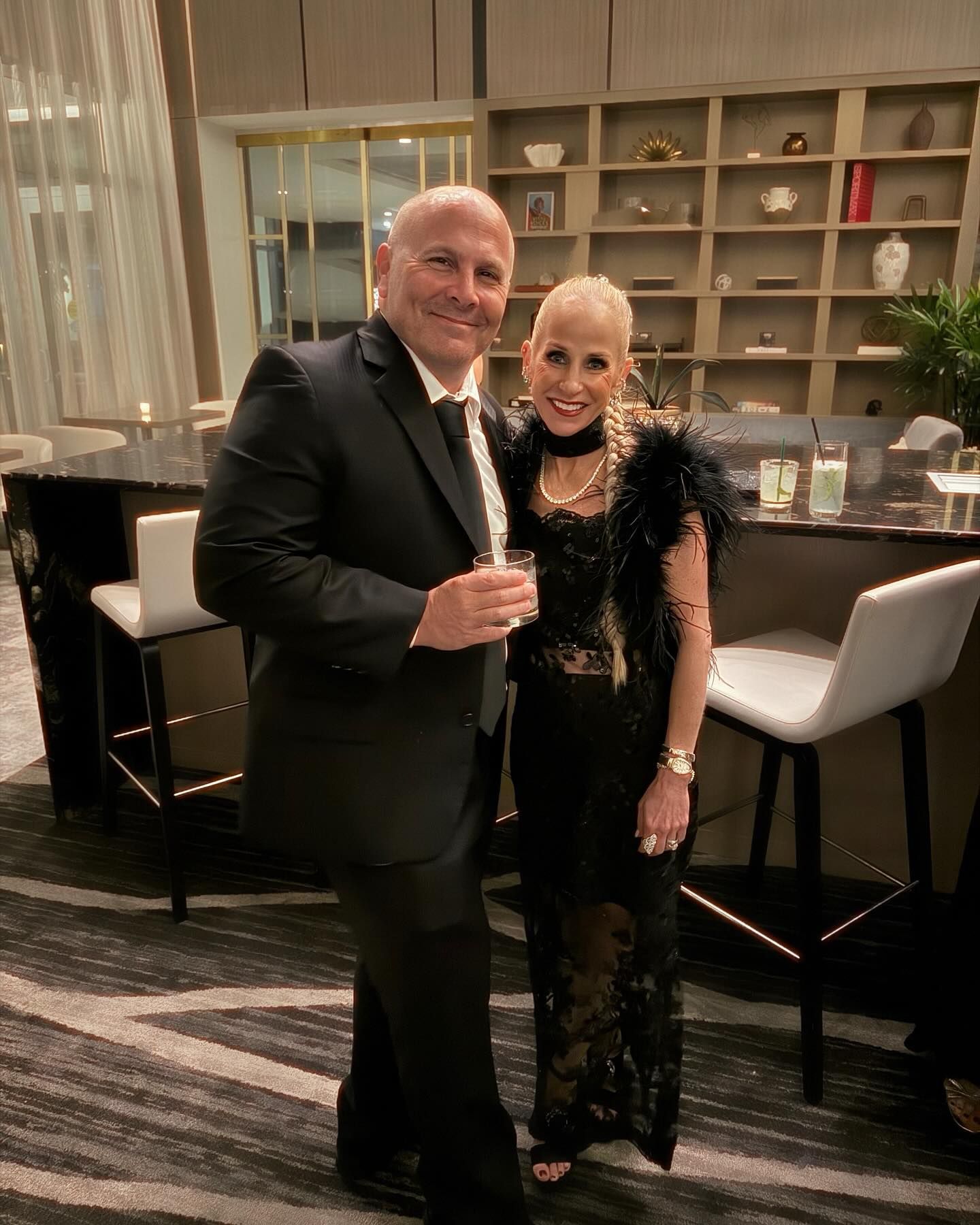 A man in a suit and a woman in a black dress are posing for a picture.