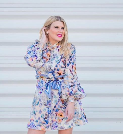A woman in a floral dress is standing in front of a garage door.