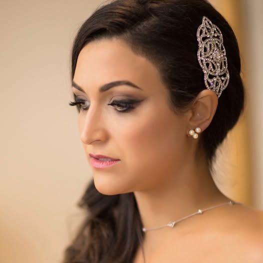 A woman wearing a necklace and earrings has a hair clip in her hair