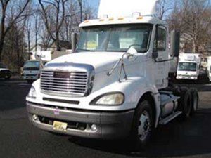 A white semi truck is parked on the side of the road