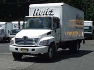 A white Hertz truck is parked in a parking lot