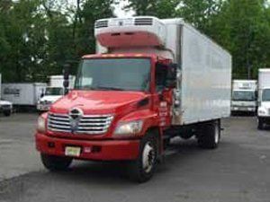 A red and white refrigerated truck is parked in a parking lot