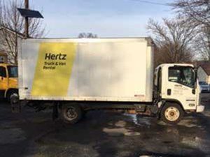 A white and yellow Hertz truck