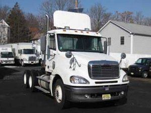 A white semi truck is parked in front of a building