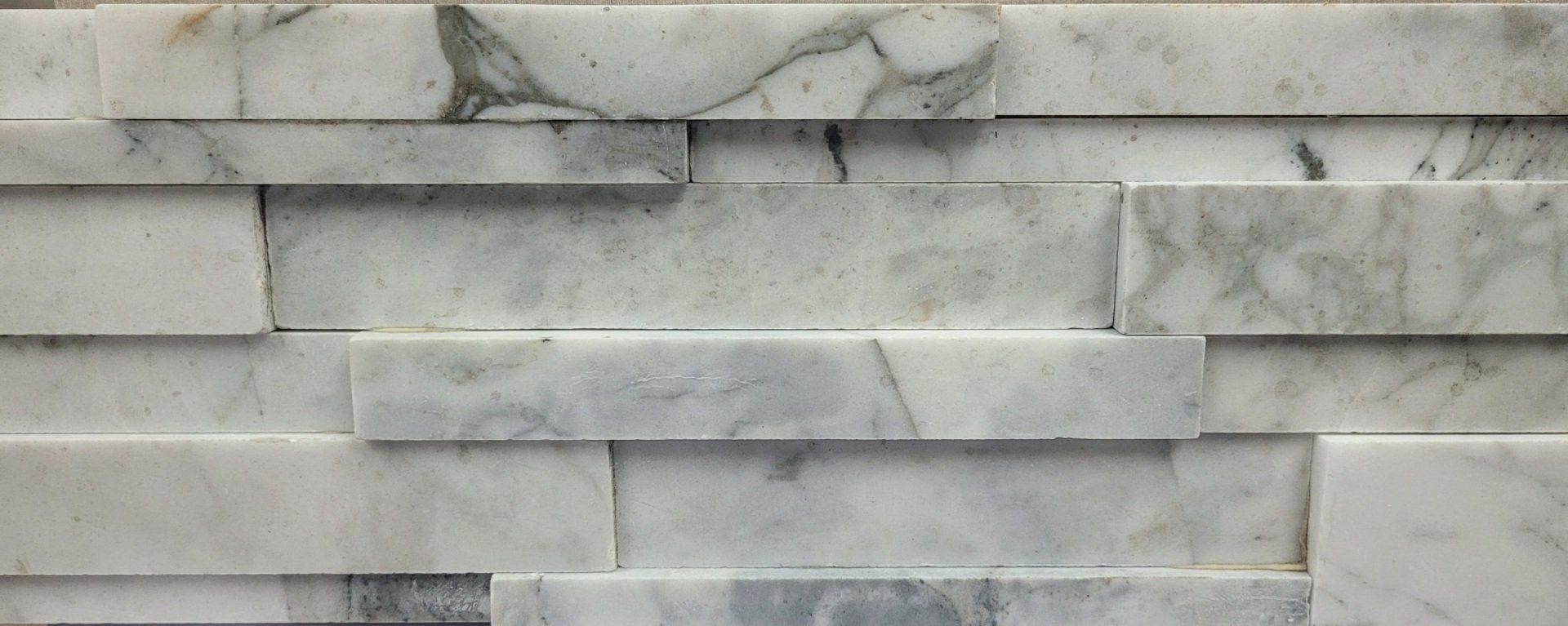 A close up of a white marble tile wall.