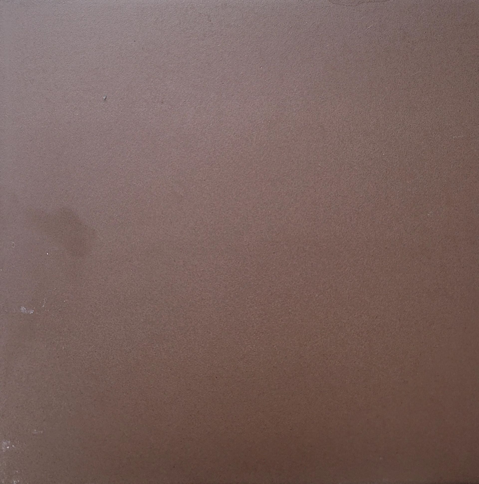 A close up of a brown tile with a grainy texture.