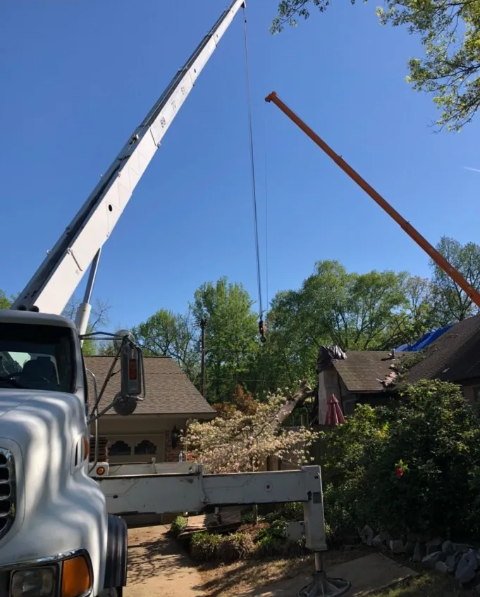 A crane lifting something in front of houses with a clear blue sky.