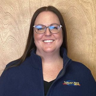Woman smiling, wearing glasses and a blue jacket with 