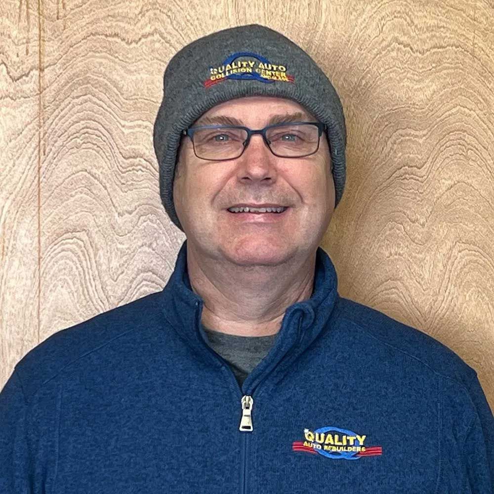 Man in glasses and beanie, wearing a blue jacket with 