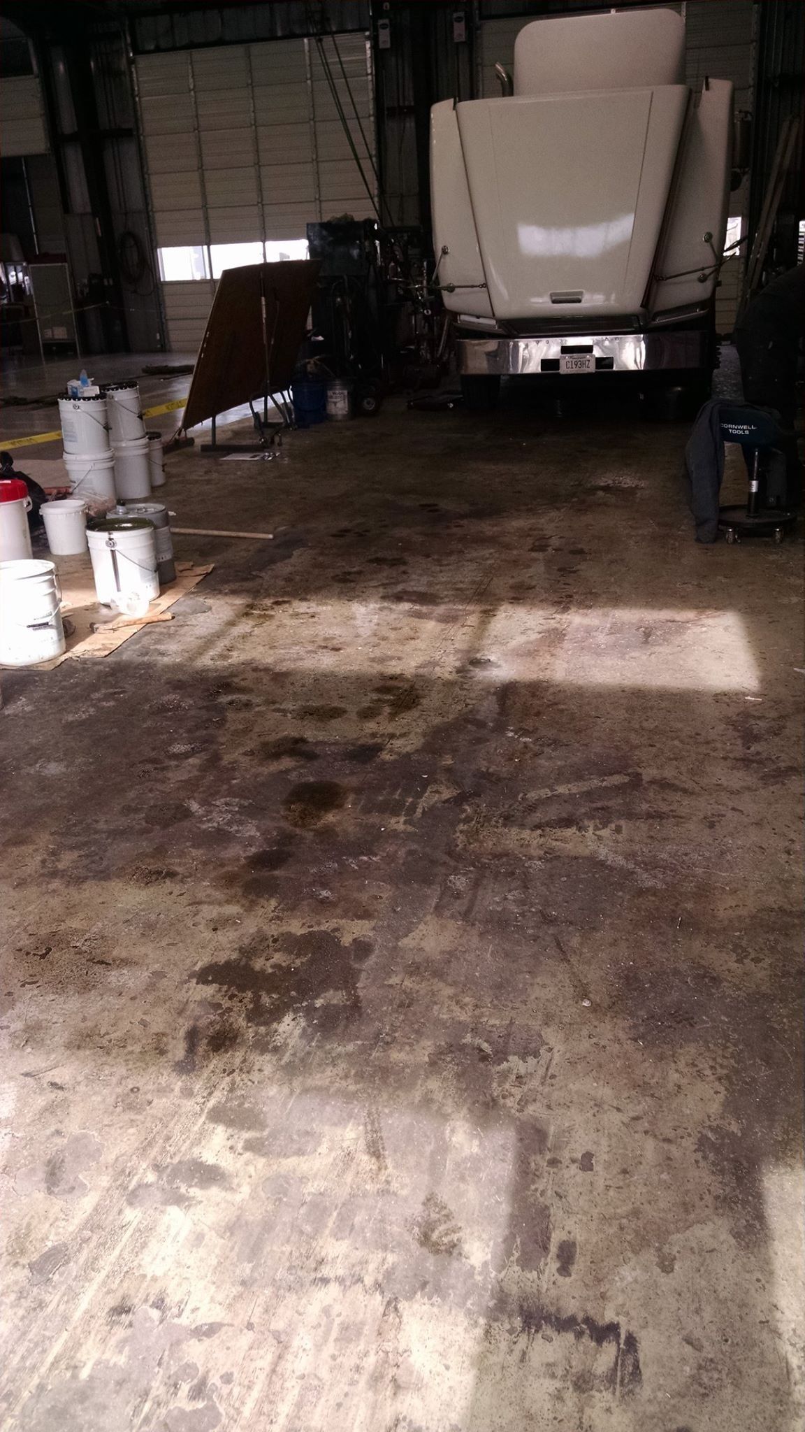 A man is standing in a dirty garage next to a truck.