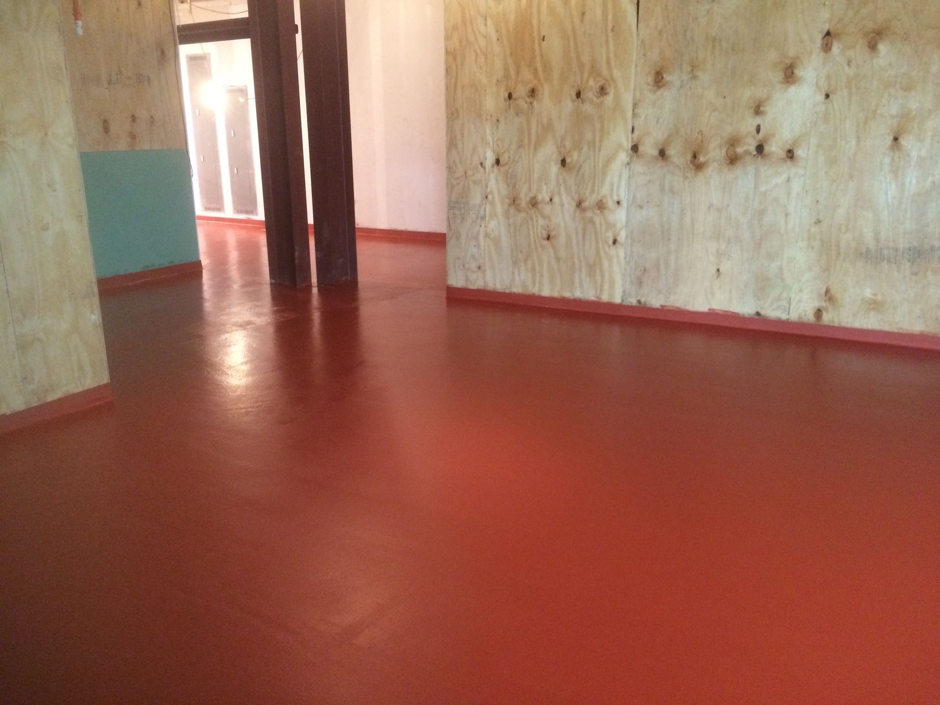 A room with a red floor and a wooden wall.
