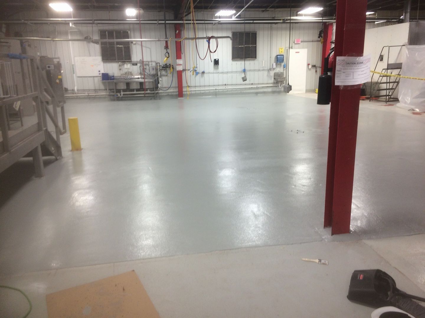 A large empty warehouse with a concrete floor and a red pillar.