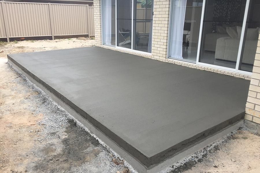 A concrete deck is being built in front of a house.