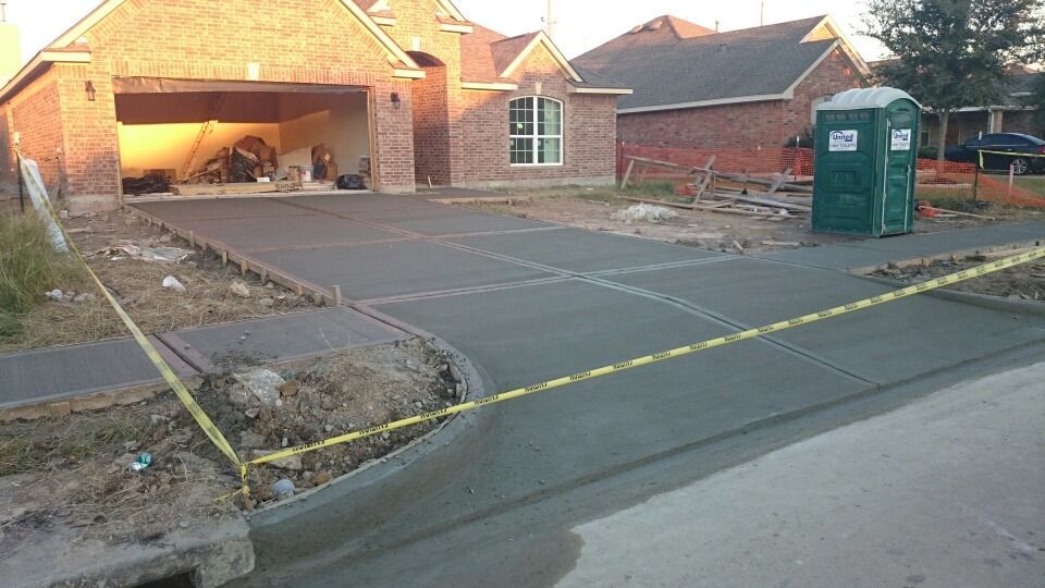 A concrete driveway is being built in front of a brick house.