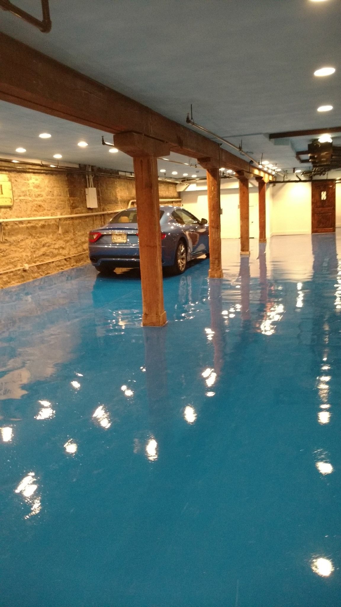 A blue car is parked in a garage with a blue floor.