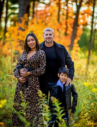 A family is posing for a picture in the woods