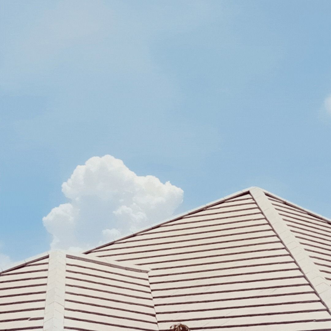 Looking up at the roof of a house with a blue sky in the background.