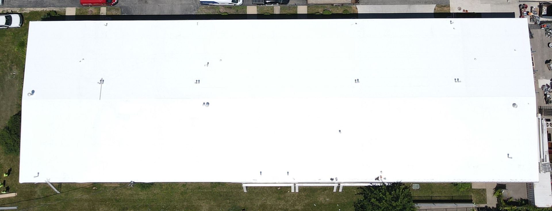 An aerial view of a large white building with a white roof replacement