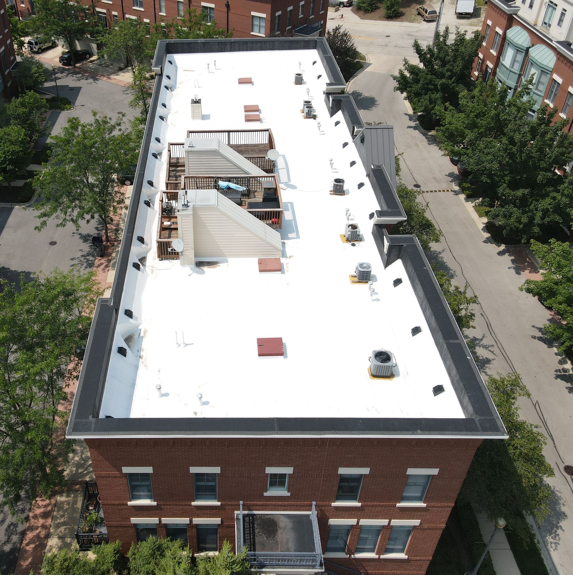 An aerial view of a brick building with a white roof
