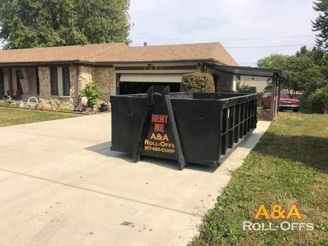 A dumpster is parked in front of a house.