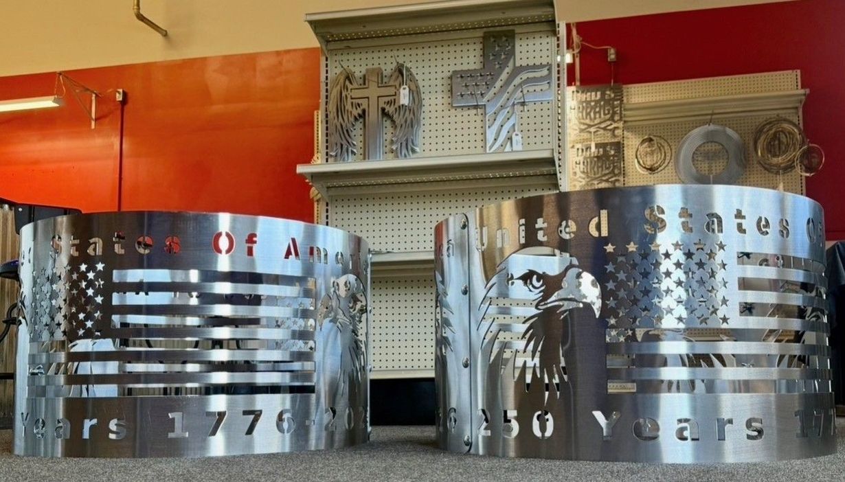 Curved metallic banners with cutout text in an indoor exhibition space against red walls