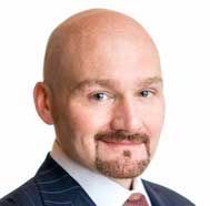 Portrait of a bald man in a suit and tie, smiling at the camera on a white background