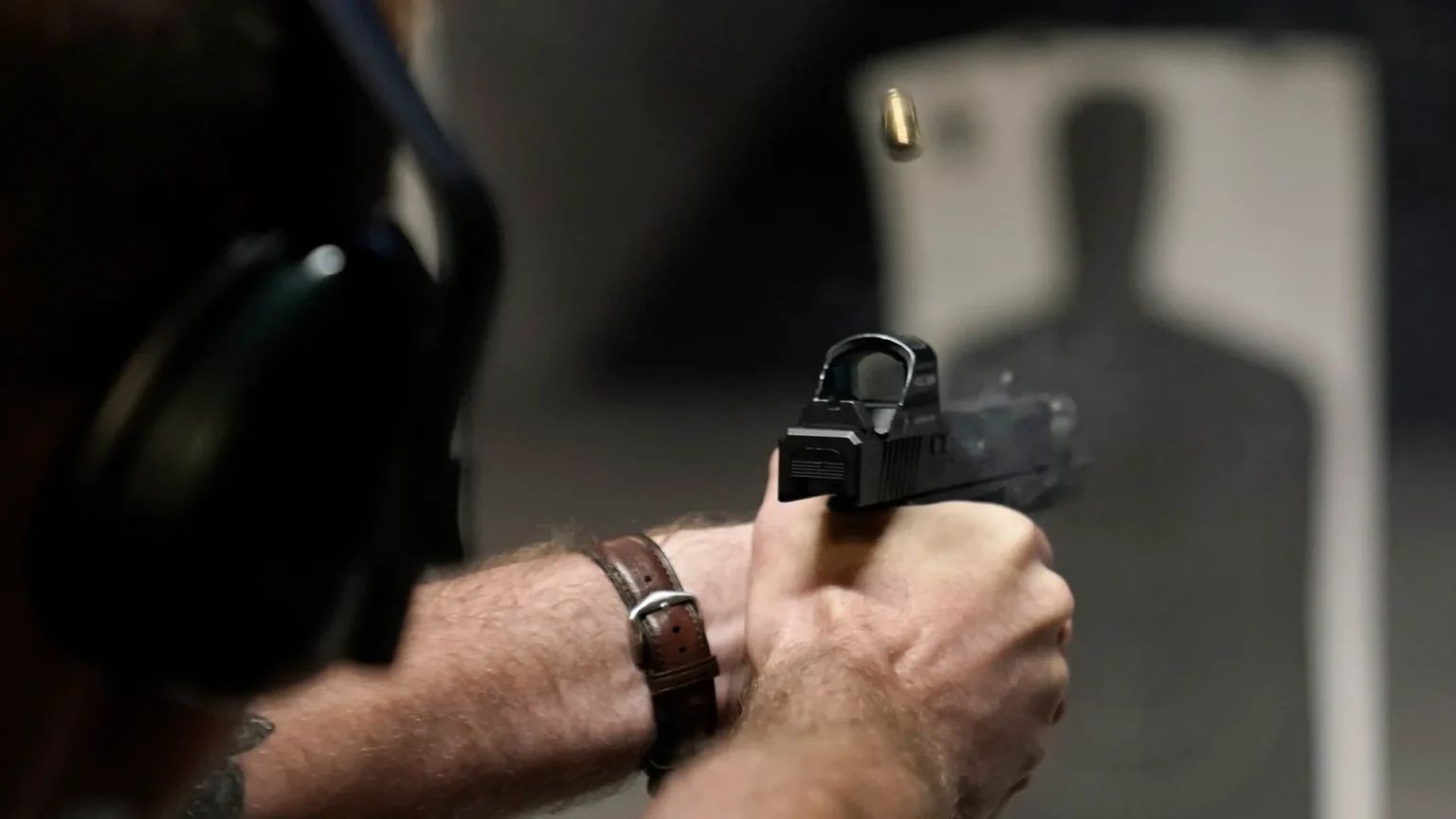 Person aiming a handgun at a shooting range target board