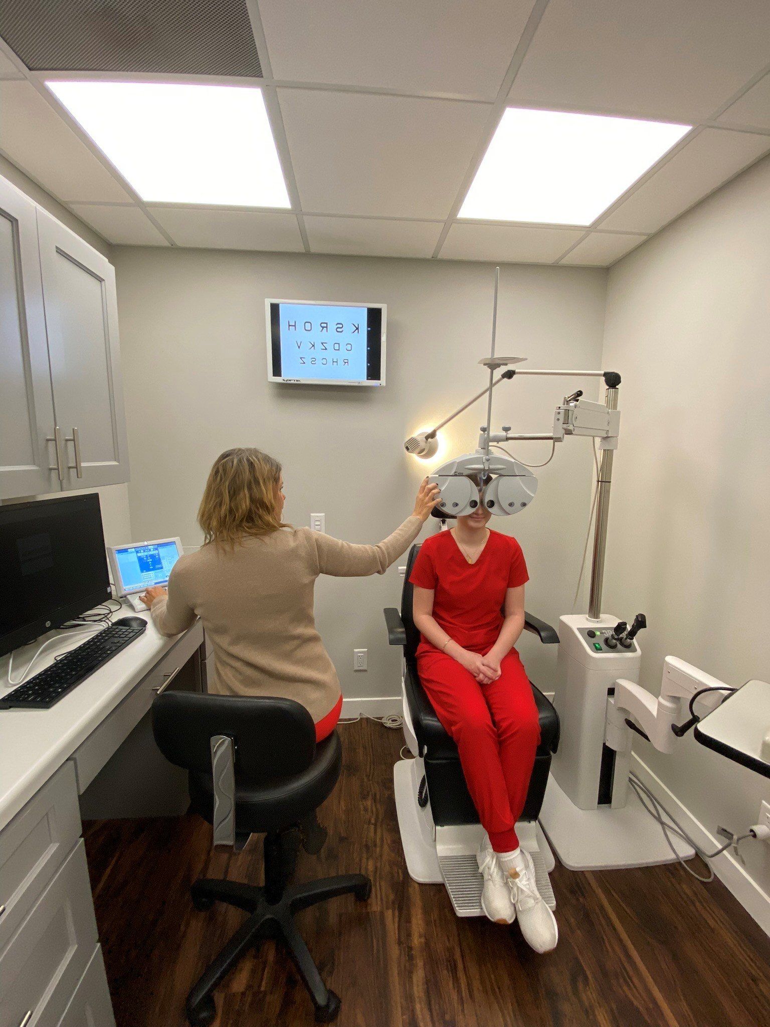 A woman is sitting in a chair getting her eyes checked by an ophthalmologist.