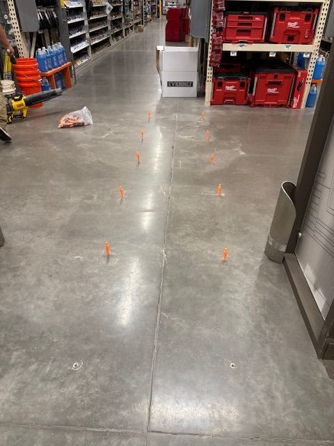 Concrete floor with orange tile spacers, likely for a tiling project, in a store aisle.