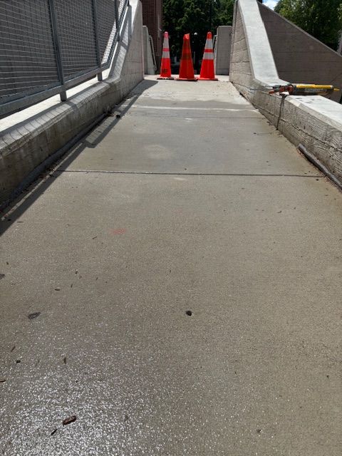 Concrete ramp, orange traffic cones, and metal railing.