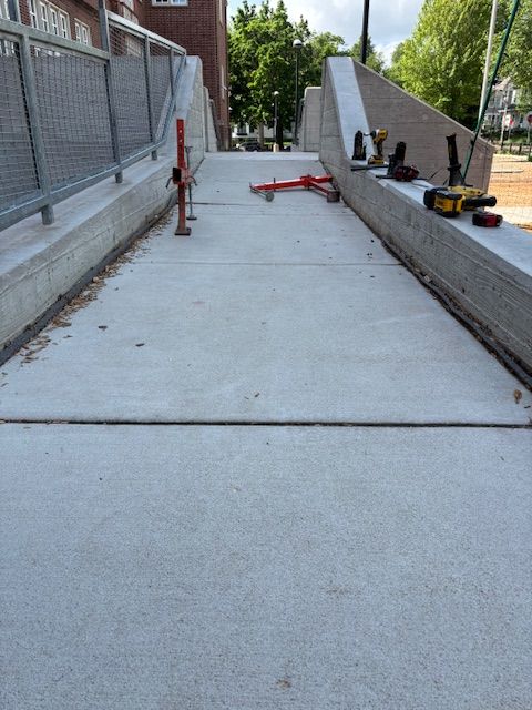 Concrete walkway with side rails; tools are visible on side ledges.
