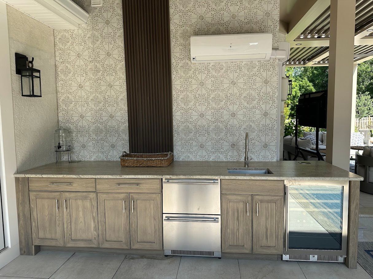 Outdoor kitchen with a weathered wood cabinet, stainless steel appliances, and tiled backsplash.