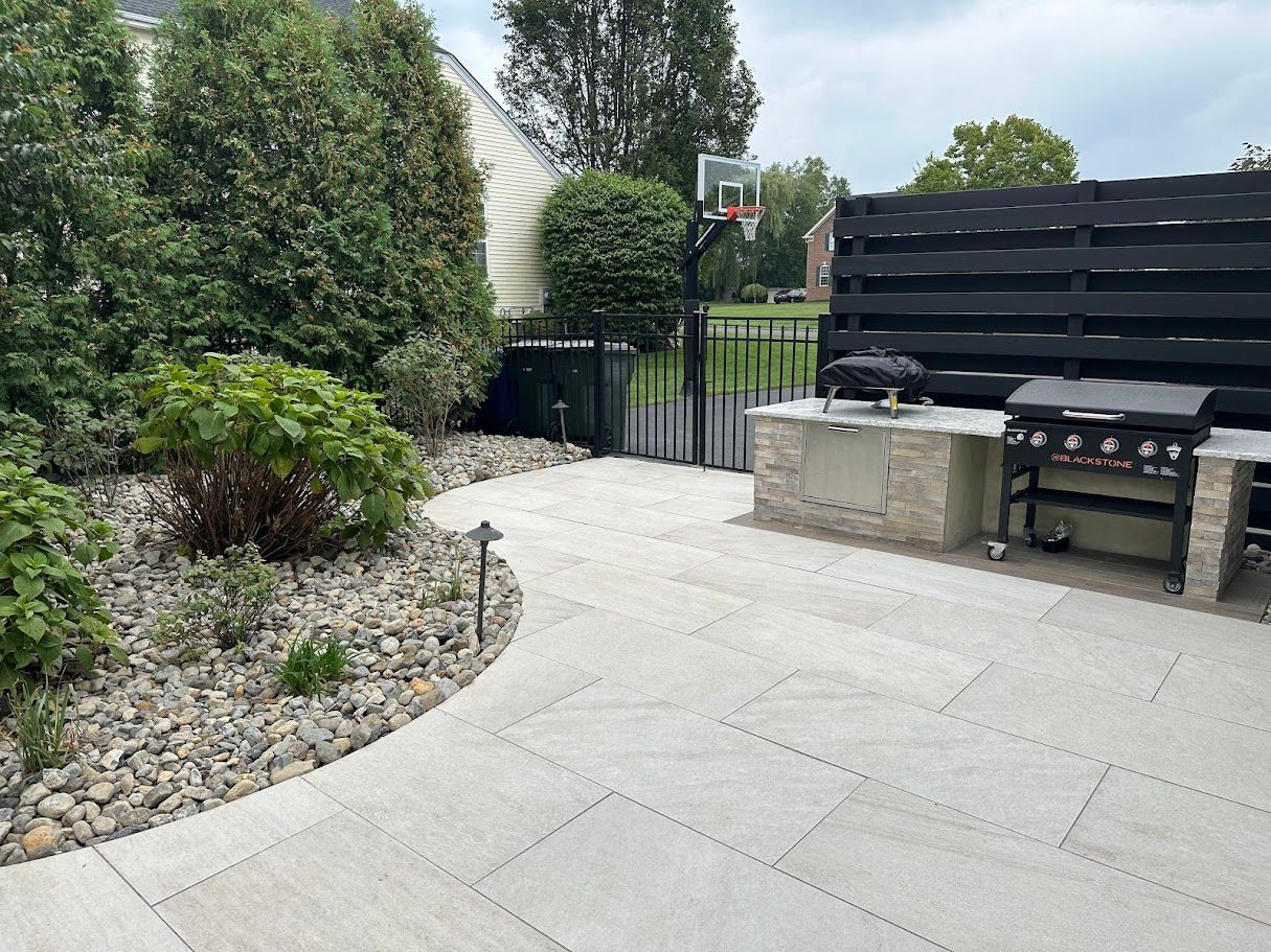 Patio with stone pavers, outdoor kitchen, and landscaping.